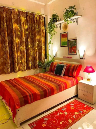 Colorful bedroom with brown leaf print curtains, vibrant striped bedding, and red decor elements, demonstrating how to mix printed curtains with solid rugs and cushions for a cohesive look.